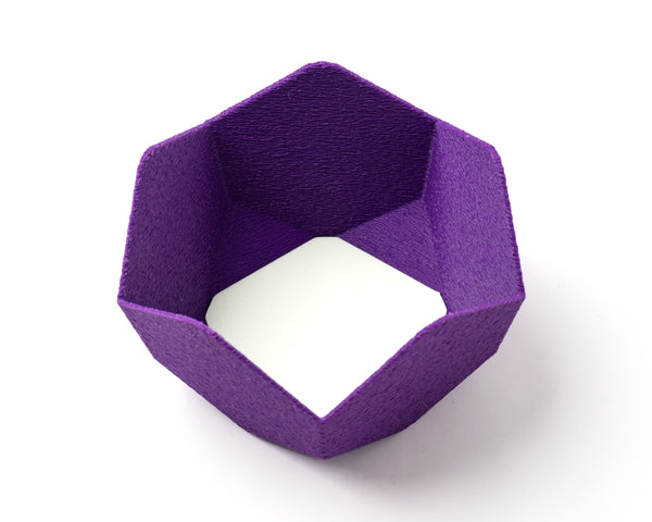 A decorative, geometric, violet catch all with an interchangeable coaster. The coaster inside is in white. 