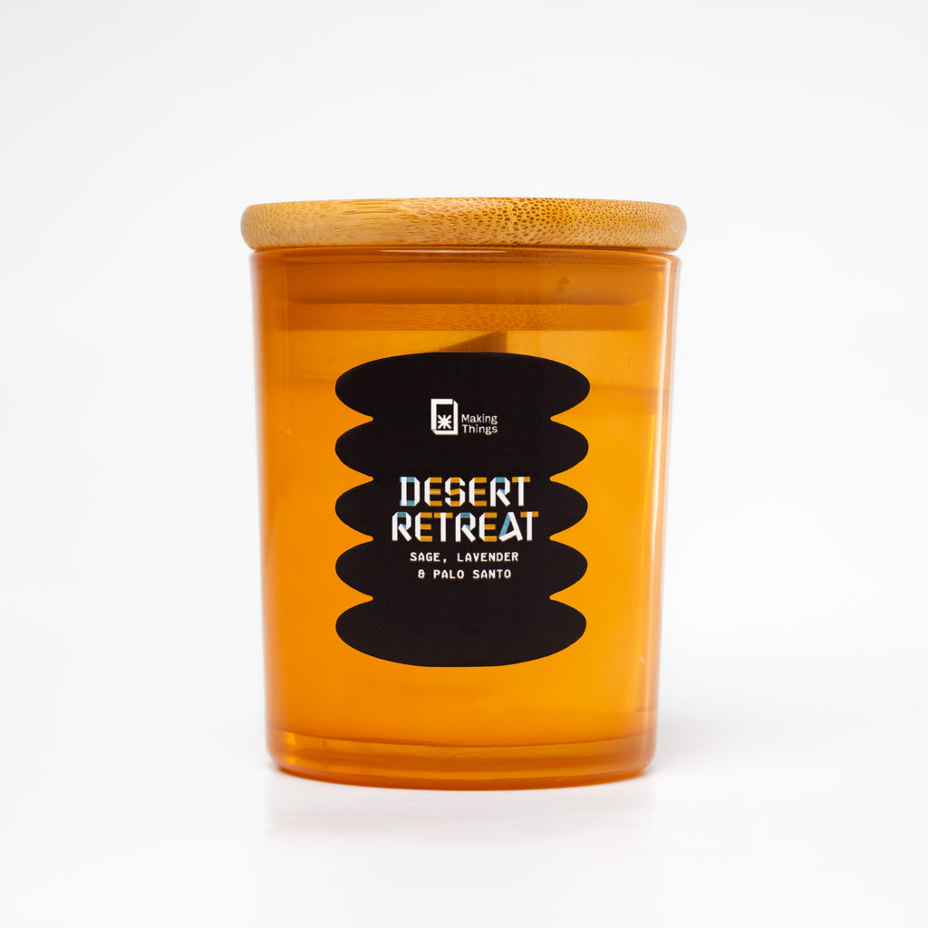 A scented candle with notes of sage, lavender, and palo santo. It is packaged in a orange jar with a wooden lid.