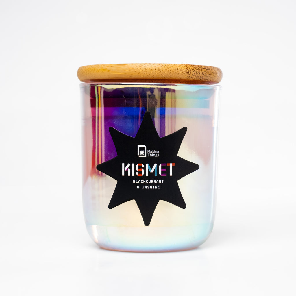 A scented candle with notes of blackcurrant and jasmine. It is packaged in an iridescent jar with a wooden lid.