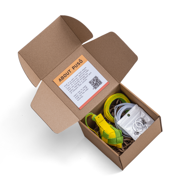 A photo of the Making Things Puso Making Kit inclusions inside its packaging. The kit includes 1 woven puso, 2 puso strips, 3 key rings, and a video tutorial.