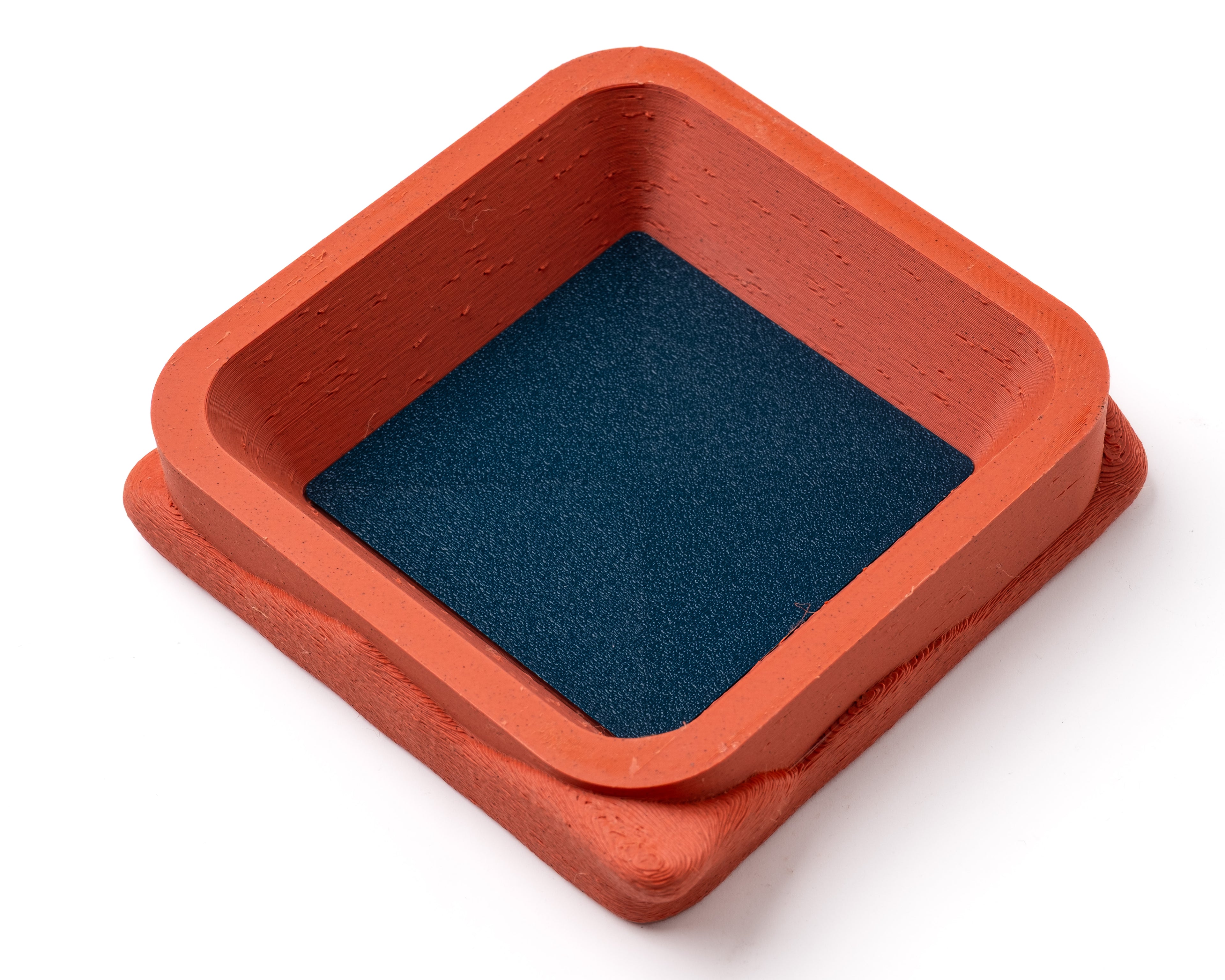 A decorative, square, orange catch all with an interchangeable coaster. The coaster inside is in black. 