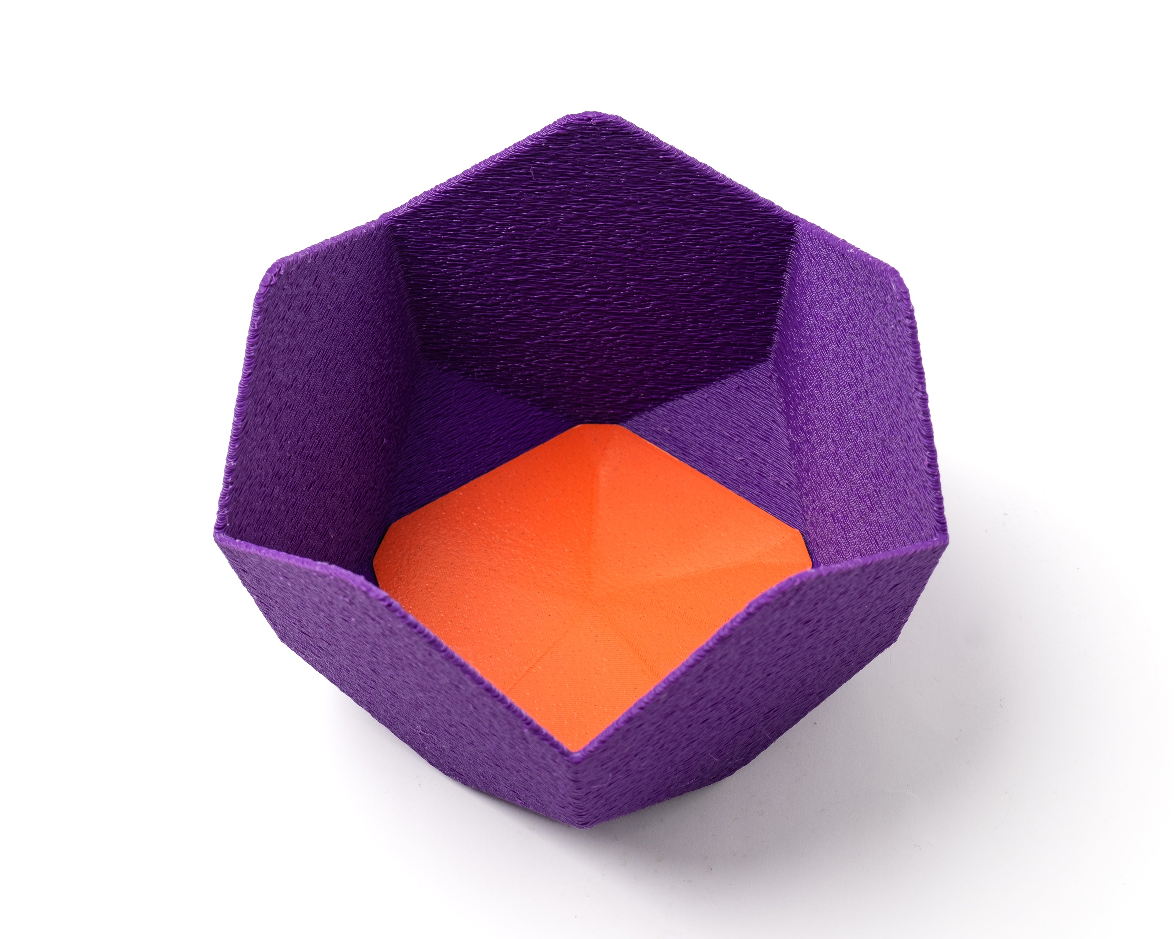 A decorative, geometric, violet catch all with an interchangeable coaster. The coaster inside is in orange. 