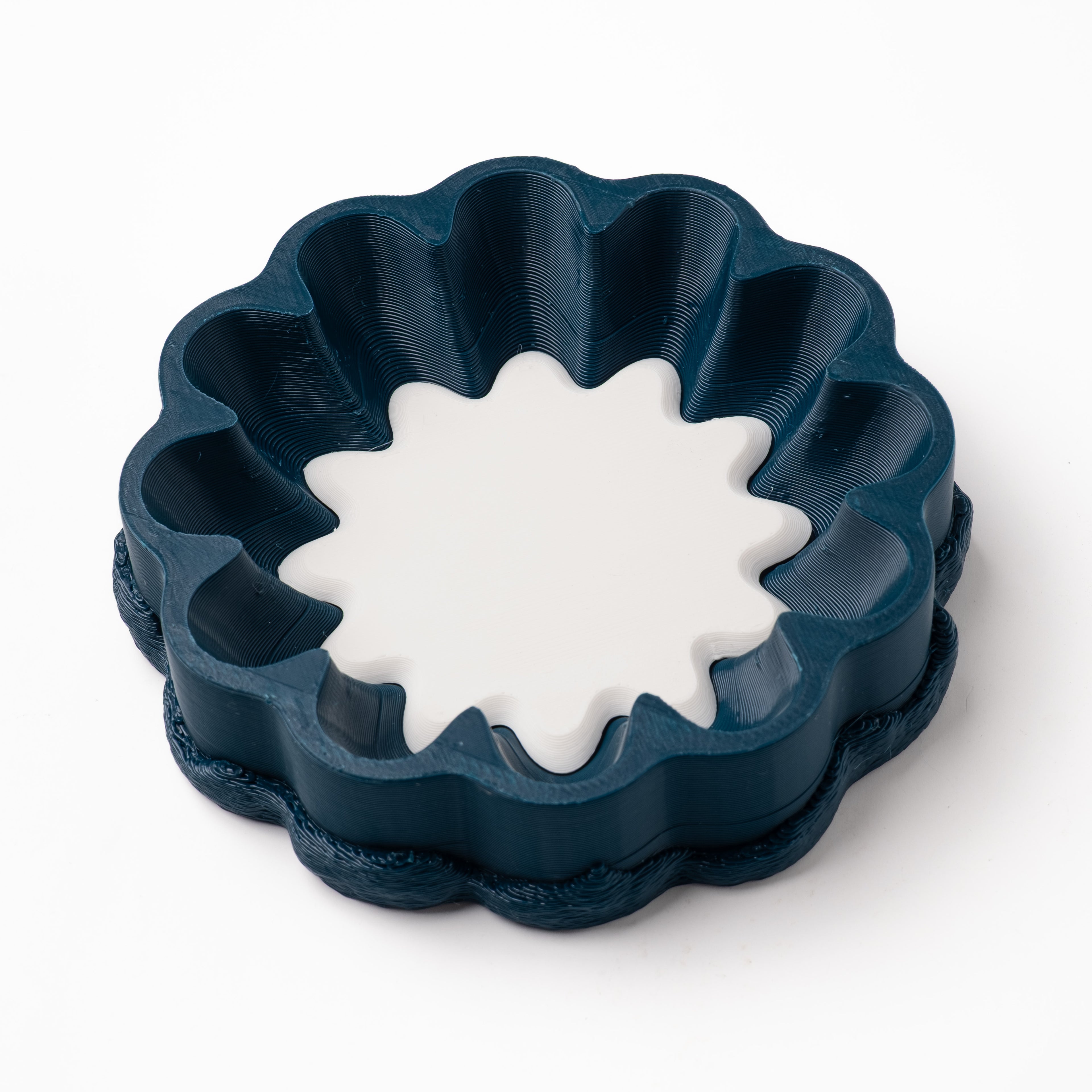 A decorative, floral-shaped, blue-green catch all with an interchangeable coaster. The coaster inside is in blue.