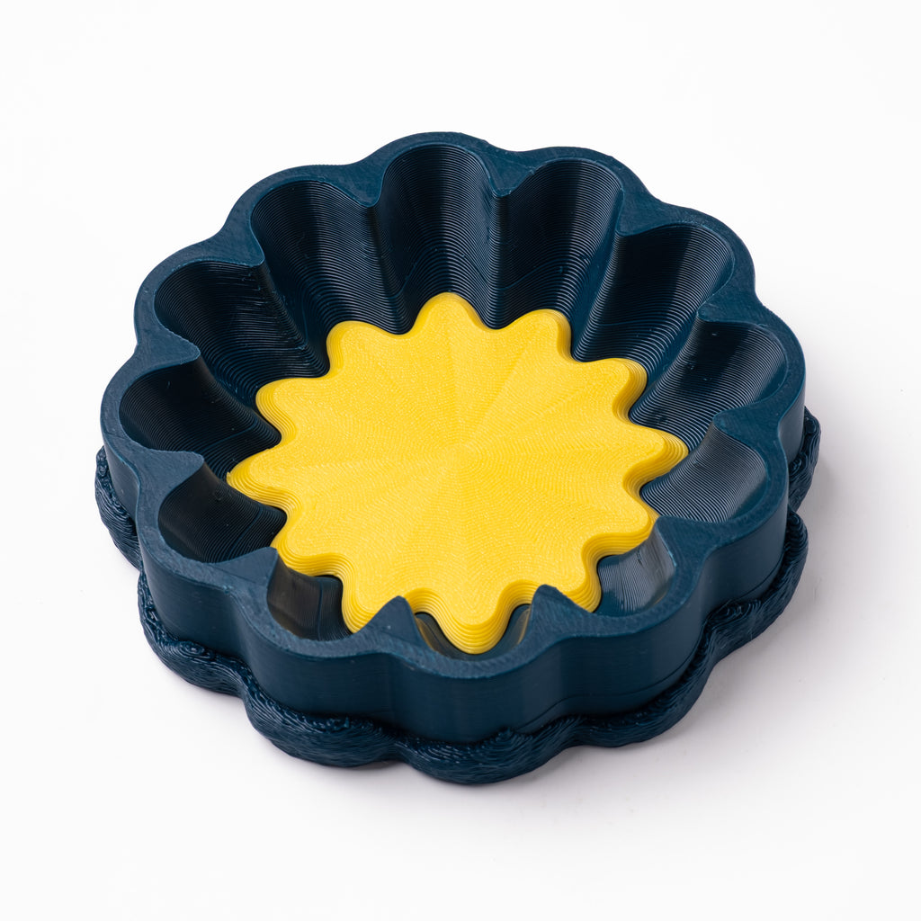 A decorative, floral-shaped, blue-green catch all with an interchangeable coaster. The coaster inside is in white. 