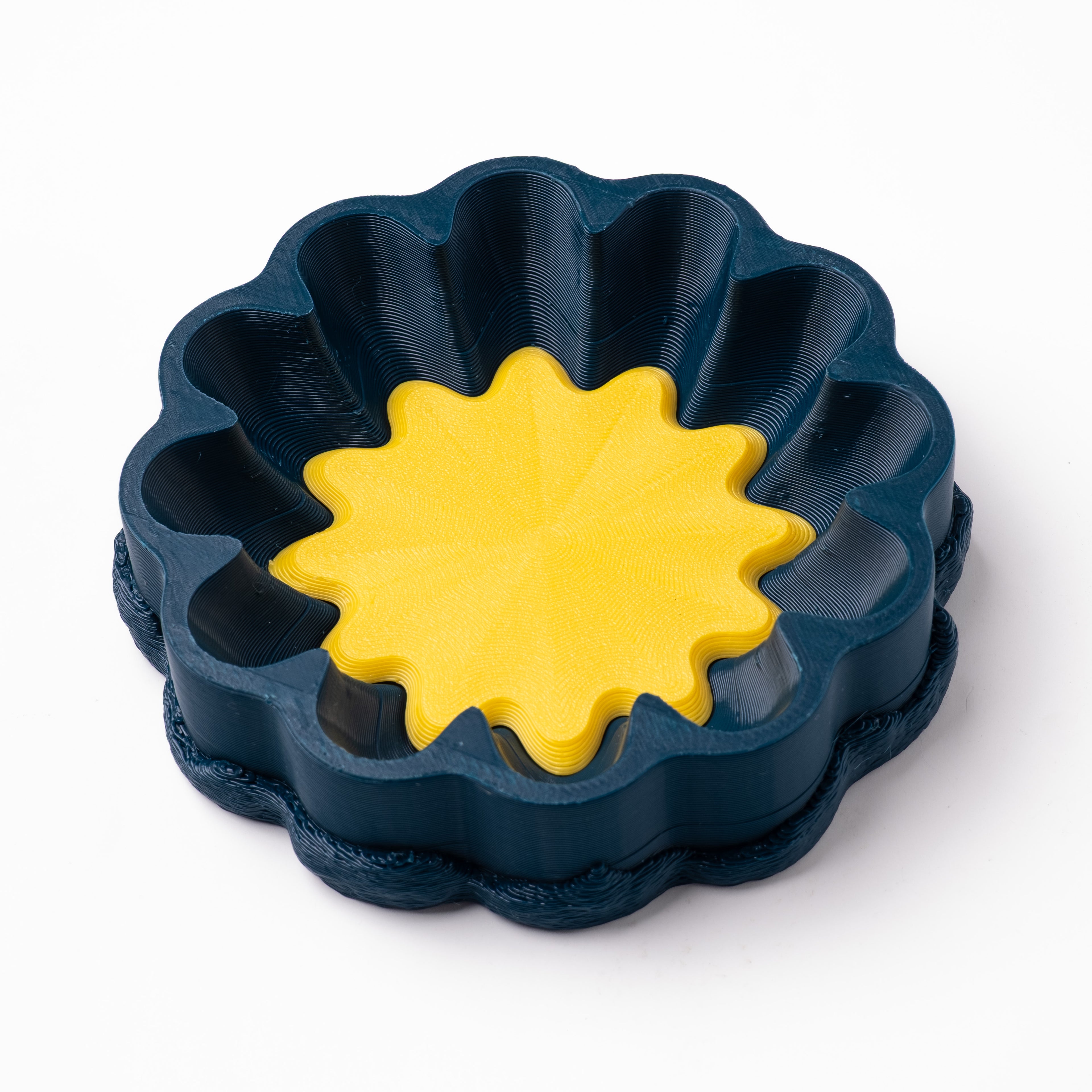 A decorative, floral-shaped, blue-green catch all with an interchangeable coaster. The coaster inside is in white. 