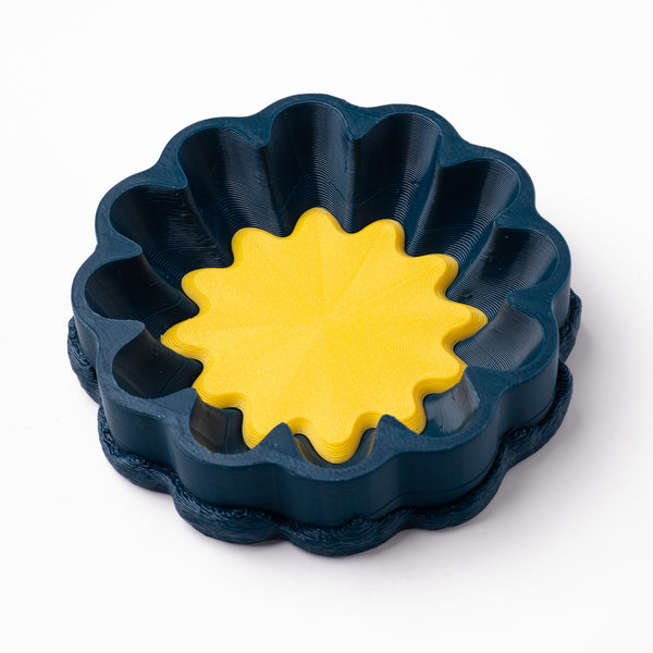 A decorative, floral-shaped, blue-green catch all with an interchangeable coaster. The coaster inside is in white. 